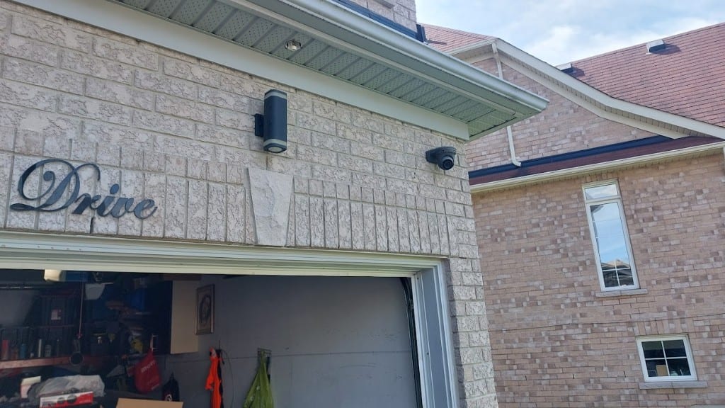 Garage dome camera installation Black dome security camera installed above a residential garage on brick exterior by Ultimate Security GTA